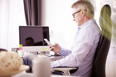 Businessman using smartphone at home office - SEGF000272