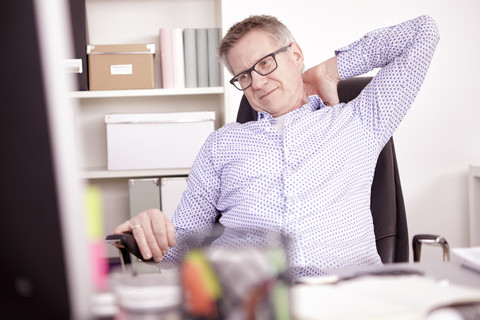 Geschäftsmann mit Nackenschmerzen im Home Office, lizenzfreies Stockfoto