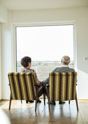 Älteres Paar sitzt nebeneinander in Sesseln und schaut durch ein Fenster - UUF003566