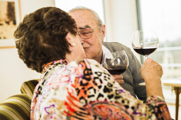 Küssendes Seniorenpaar mit Rotweingläsern - UUF003581