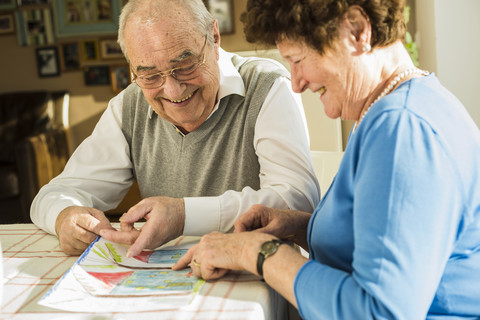 Glückliches älteres Ehepaar betrachtet die Zeichnung eines Kindes, lizenzfreies Stockfoto