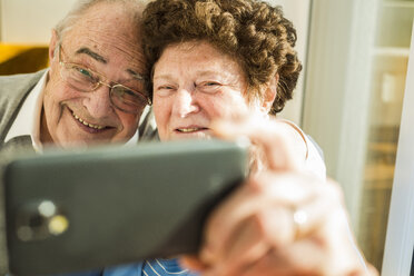 Senior couple taking a selfie with smartphone at home - UUF003592