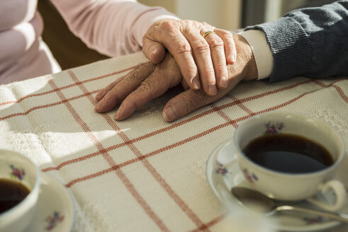 Älteres Paar hält sich in der Kaffeepause an den Händen - UUF003595