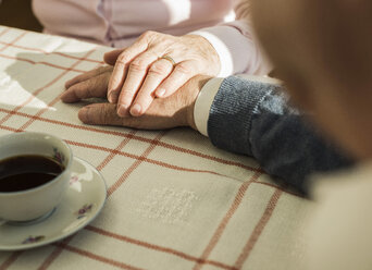Senior couple holding hands at coffee break - UUF003596