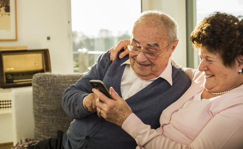 Älteres Paar nutzt Smartphone zu Hause, lizenzfreies Stockfoto