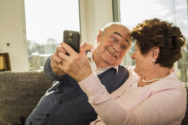 Senior couple taking a selfie with smartphone at home - UUF003612