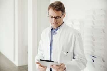Mature man in lab coat using digital tablet - MFF001530