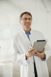 Smiling mature man in lab coat holding digital tablet - MFF001543