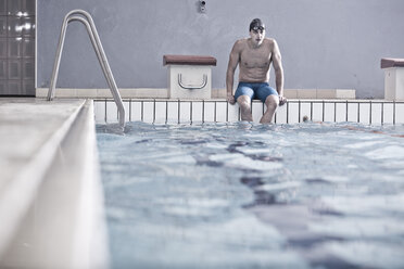 Swimmer in indoor pool sitting on pool edge - ZEF004721