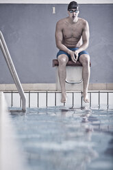Schwimmer im Hallenbad auf dem Startblock sitzend - ZEF004722