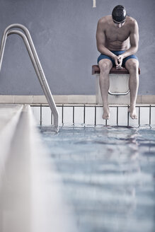 Schwimmer im Hallenbad auf dem Startblock sitzend - ZEF004723