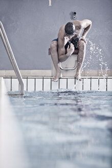 Schwimmer im Hallenbad auf dem Startblock sitzend - ZEF004724