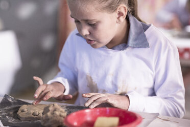 Girl working on modeling clay in art class at school - ZEF005966