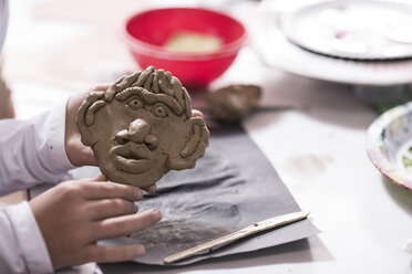 Boy making face from modeling clay in art class at school - ZEF006137