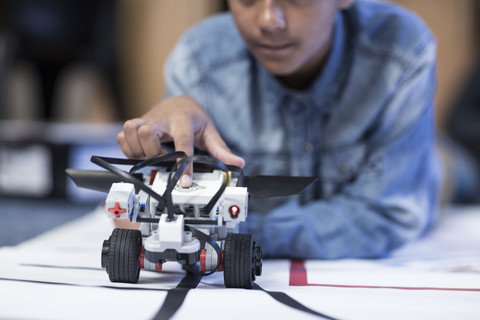 Schoolboy in robotics class testing vehicle on test track stock photo