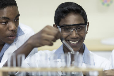 Two students in chemistry class pipetting liquid into test tube - ZEF006130