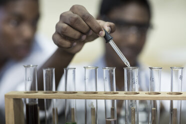 Student in chemistry class pipetting liquid into test tube - ZEF006132
