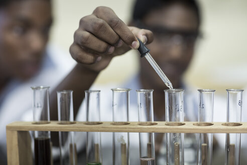 Schüler im Chemieunterricht, der Flüssigkeit in ein Reagenzglas pipettiert - ZEF006132