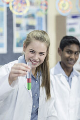 Smiling schoolgirl in chemistry class holding test tube - ZEF006138