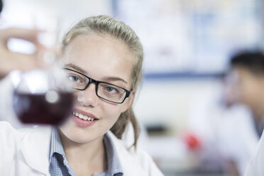 Lächelndes Schulmädchen im Chemieunterricht mit Blick auf einen Rundkolben - ZEF006147
