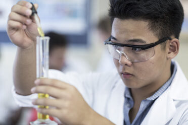 Student in chemistry class pipetting liquid into test tube - ZEF006153