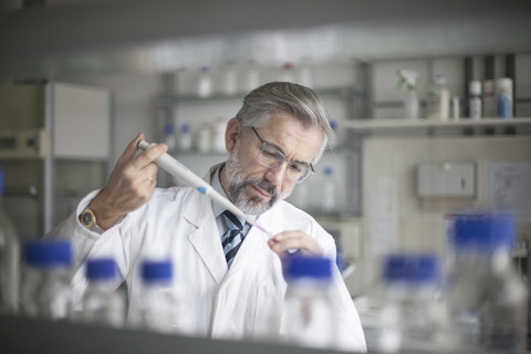 Wissenschaftler gießt Flüssigkeit in Reagenzglas, lizenzfreies Stockfoto