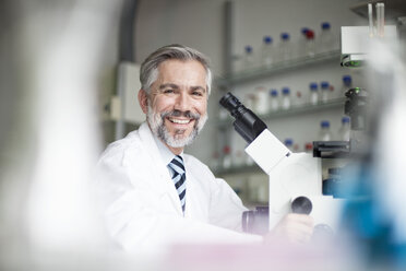 Porträt eines lächelnden Wissenschaftlers im Labor mit Mikroskop - RBF002571