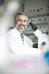 Porträt eines lächelnden Wissenschaftlers im Labor mit Mikroskop - RBF002529