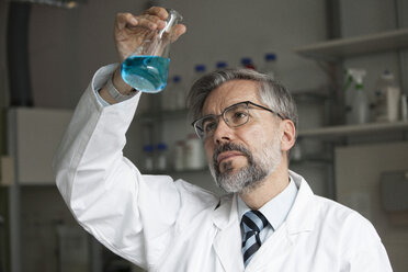 Wissenschaftlerin im Labor, die eine Flüssigkeit im Erlenmeyerkolben untersucht - RBF002537