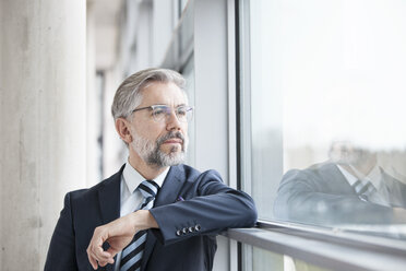 Thoughtful businessman looking out of window - RBF002554