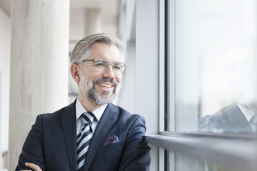 Confident businessman looking out of window - RBF002556