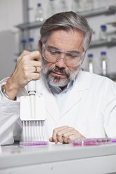 Scientist pipetting in laboratory - RBF002569