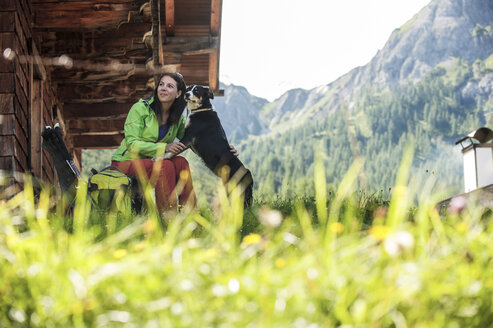 Österreich, Altenmarkt-Zauchensee, junge Frau mit Hund auf Almhütte - HHF005170