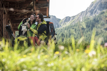 Austria, Altenmarkt-Zauchensee, young couple with dog at alpine cabin - HHF005176