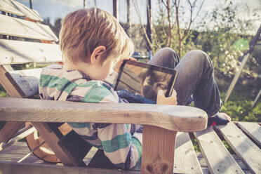 Junge spielt mit digitalem Tablet auf Holzliege - SARF001567
