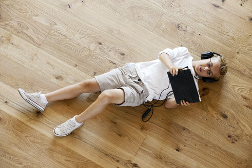 Junge auf Holzboden liegend mit digitalem Tablet - LBF001080
