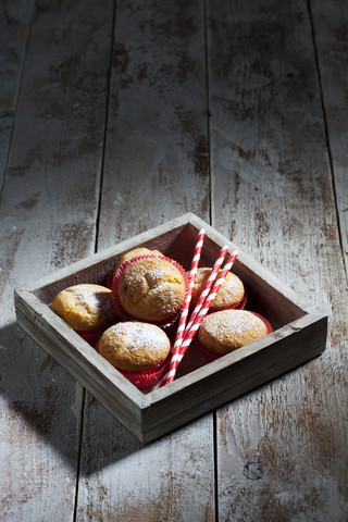 Holztablett mit Muffins und Trinkhalmen auf Holz, lizenzfreies Stockfoto