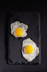 Fried quail egg and fried hen's egg on slate - CSF025003