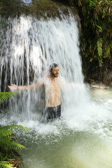 Philippinen, Siquijor, Mann genießt das fließende Wasser des Cambugahay-Wasserfalls - GEMF000130