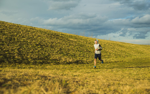 Deutschland, Mannheim, junger Mann joggt auf einer Wiese, lizenzfreies Stockfoto