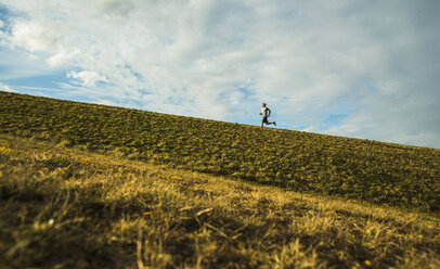 Germany, Mannheim, young man jogging in meadow - UUF003631