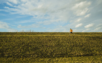 Germany, Mannheim, young man jogging in meadow - UUF003632