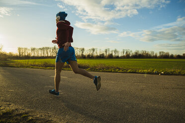 Deutschland, Mannheim, junger Mann joggt auf Landstraße - UUF003639
