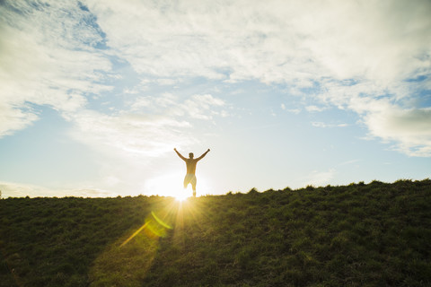 Germany, Mannheim, cheering young man looking at rising sun stock photo