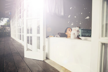 Woman in bathtub blowing foam - MBEF001341