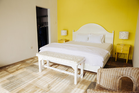 Indonesien, Bali, Schlafzimmer mit gelber Wand und gelben Nachttischen in einer Ferienvilla, lizenzfreies Stockfoto