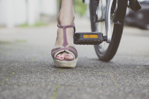 Close-up of woman with wedges on bicycle - CHPF000114