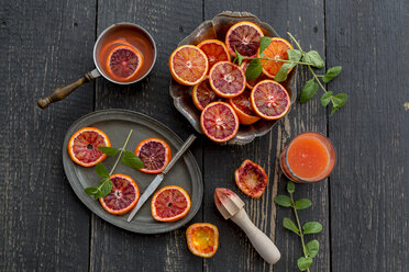 Sliced blood oranges and glass of blood orange juice on wood - SARF001535