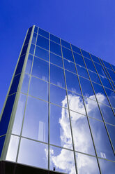Deutschland, Bielefeld, Glasfassade eines Geschäftshauses mit Wolkenreflexion - HOHF001306