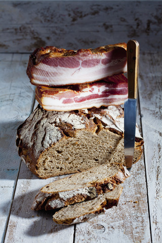 Laib und Scheiben von Schwarzbrot, Speck und Messer, lizenzfreies Stockfoto